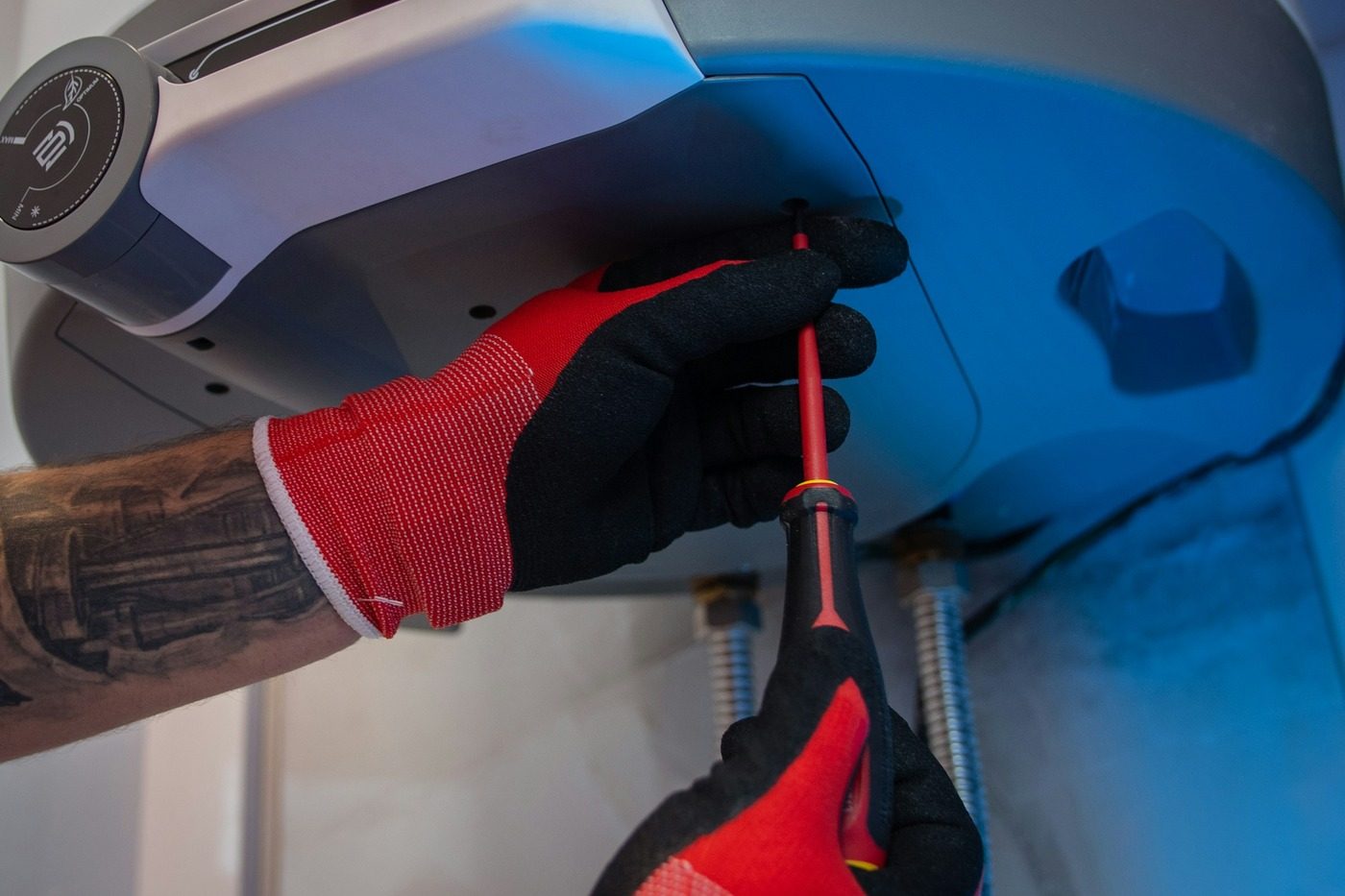 Tecnico con i guanti che apre il mantello di una caldaia per la manutenzione